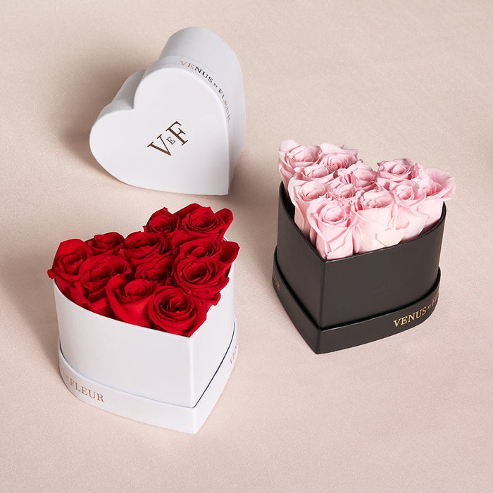 Three heart-shaped flower boxes: one white box with red roses, one black box with pink roses, and one white box lid with 'VEF' and 'VENUS ET FLEUR' text.